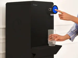 Czarny, nablatowy dystrybutor wody Culligan Purity. Osoba w niebieskiej koszuli napełnia wodą szklankę i wybiera opcję na dotykowym ekranie. Na obudowie widać logo Culligan.