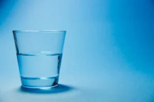 Szklanka filtrowanej wody Culligan na niebieskim tle.