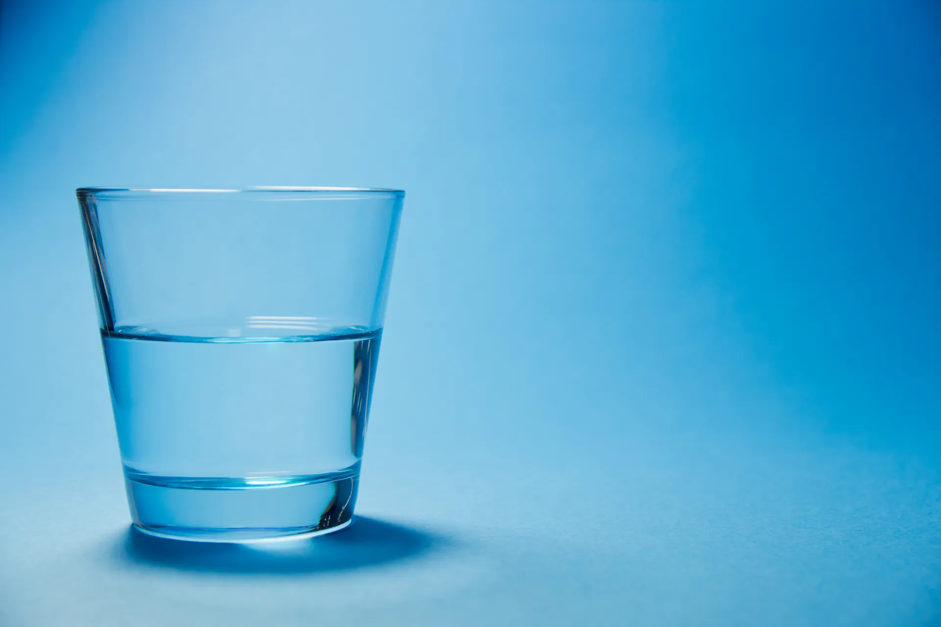 Szklanka filtrowanej wody Culligan na niebieskim tle.